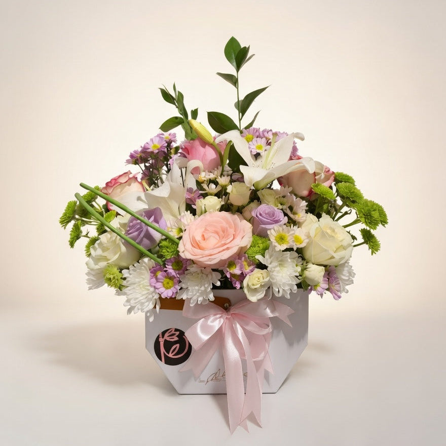 Floral arrangement in a box with a pink bow on a light background