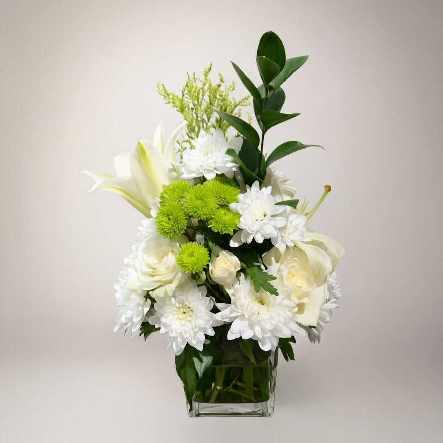 Bouquet of white and green flowers in a clear vase on a light background