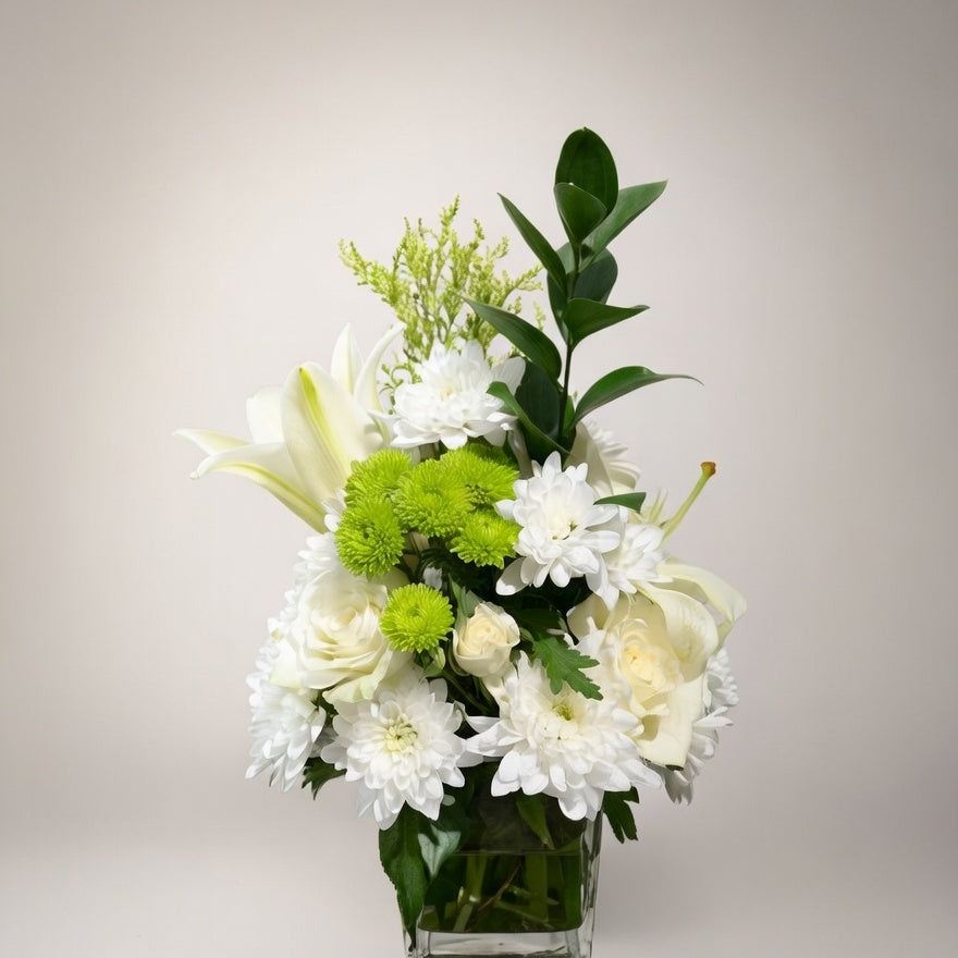 Bouquet of white and green flowers in a clear vase on a light background