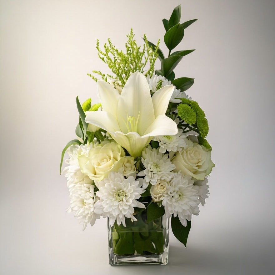 Floral arrangement with white and green flowers in a clear vase on a light background